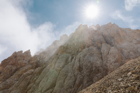 Majestic rocky cliffs and sharp stone peaks of Mount Shalbuzdag surrounded by light clouds and sunbeams in Dagestan, Russia, offering an atmospheric high altitude mountain landscape