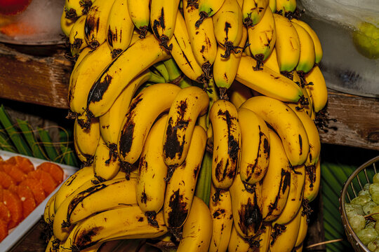 Large bundle of fresh ripe yellow bananas hanging in a market display.