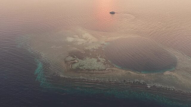 Sunrise illuminates a small ship at a remote coral reef near Halmahera, Indonesia. This beautiful region is home to extraordinary marine biodiversity and is a destination for divers and snorkelers.