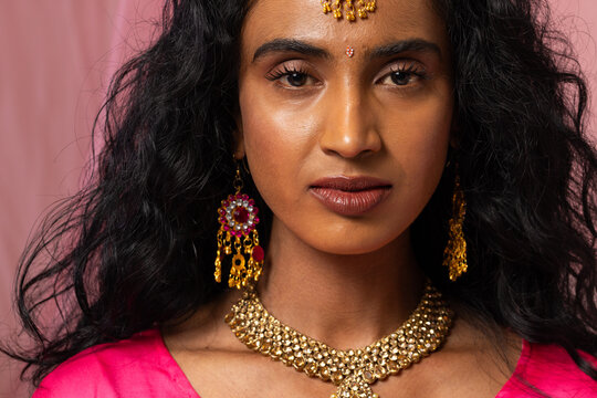 Indian woman posing in studio, wearing gold choker, maang tikka, pink blouse, bindi