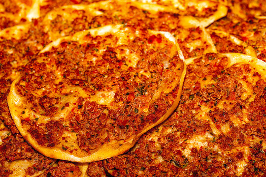 Traditional Turkish lahmacun with minced meat and herbs on a wooden board.