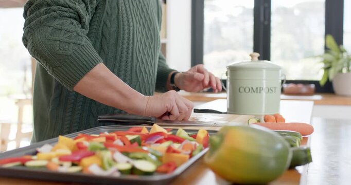 Placing tray, cook is chopping and arranging veg on counter for roasting, using compost pail