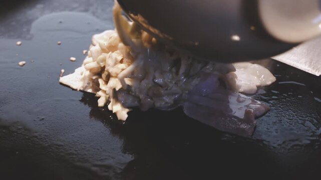 鉄板の上で炒めるお好み焼きの生地、刻みキャベツや具材を混ぜ合わせて焼く調理シーン
