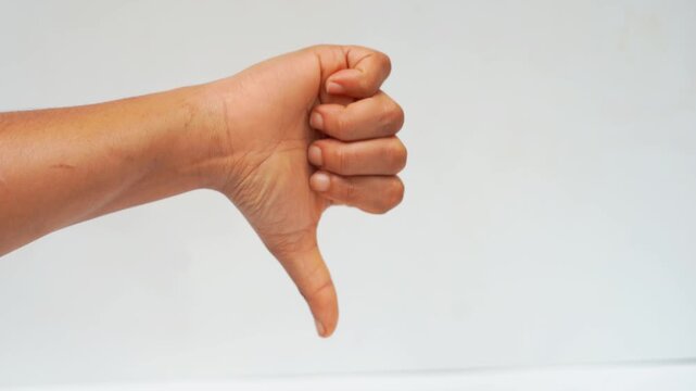 Hand Showing Thumbs Down Gesture to Express Dislike and Disapproval on White Background.