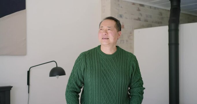 Camera zooming in, Asian man responding to prompt, turning and laughing in bedroom, showing watch