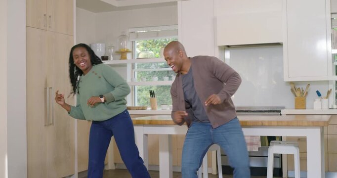 African American couple dancing to music swinging, high fiving, man easing onto stool