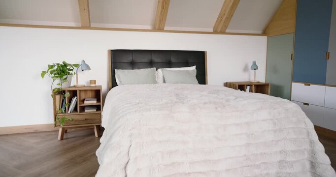 Camera is pulling back from bed, rising and revealing headboard and lamps to showcase loft bedroom