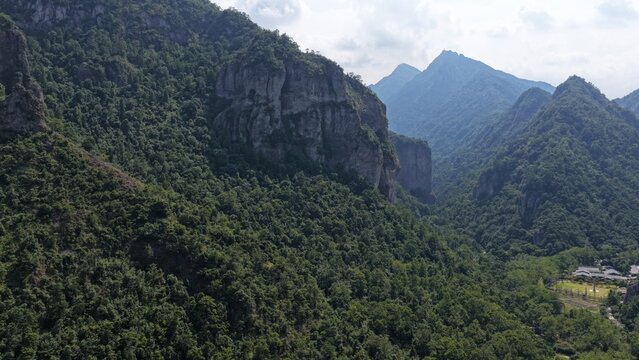 Aerial view of towering karst mountains in Lingfeng, Yandangshan, China, with a traditional temple nestled below. Dramatic limestone peaks and lush vegetation dominate the landscape.
