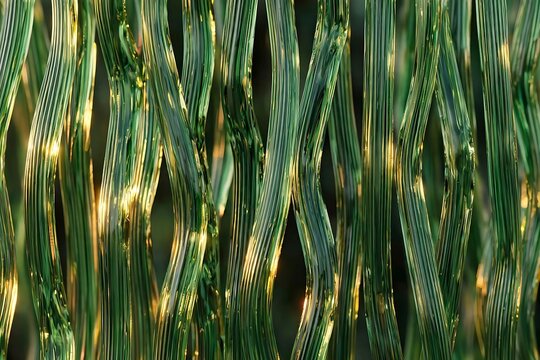 Abstract background of vertical wavy green glass rods with golden light reflections with reflections shadows repeating create abstract texture transparent translucent glow