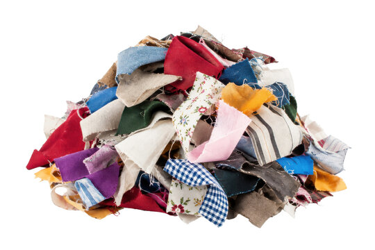 Large pile of colorful fabric scraps and textile remnants is neatly arranged on a clean white background, showcasing various textures and patterns