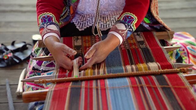 Slow-motion close-up of Andean hands weaving while wearing colorful traditional Peruvian clothing