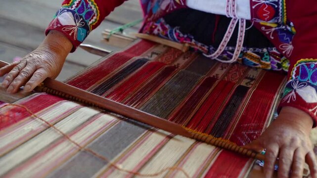 Slow-motion close-up of Andean hands weaving while wearing colorful traditional Peruvian clothing