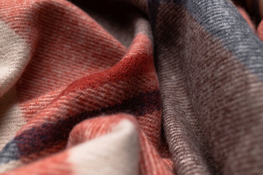 Cozy checkered textile fills frame with flowing folds and tactile weave, combining muted red, brown, gray and cream tones. Soft fabric supports apparel design, home decor and autumn campaigns.