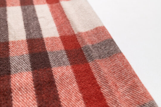 Seasonal plaid fabric shows red, gray and beige checks in detailed close view with clean background space. Woven pattern fits autumn fashion campaigns, textile catalogs and clothing design concepts.