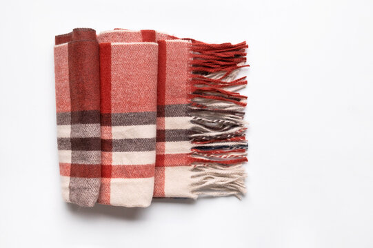 Folded checkered scarf with fringe appears on pale gray surface, featuring burgundy and neutral tones. Cozy fashion content highlights seasonal accessories, textile design, fall styling and comfort.