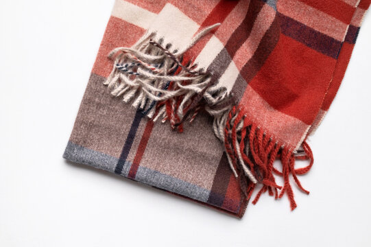 Checked textile scarf with fringed edges sits on neutral gray background, combining burgundy, beige and gray bands. Retail imagery suits fall collections, accessory catalogs, fashion layouts.
