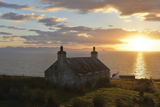 Evening view, short before sunset, Isle of Skye on a single track road with an old Scottish stone house, Melvaig, Gairloch, Western Ross, Scotland, United Kingdom