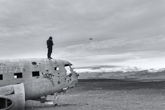 Man on aircraft wreck Douglas DC-3 controls Drone, S&oacute;lheimasandur, Solheimasandur, near Ring Road, Su&eth;urland, Sudurland, South Iceland, Iceland