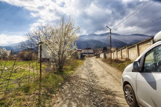 Campervan on the road, driving on unpaved dirt road, blossoms of a fruit tree, awakening nature in spring, mountains, Kjustendi Oblast, Bulgaria