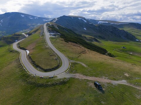 Curvy road leads through green mountains with a wide view of the surrounding countryside, aerial view, motorhome, camper, near R&acirc;nca, Ranca, Transalpina high road, Drum național 67C, national road, Transylvania Alps, South Carpathians, Romania