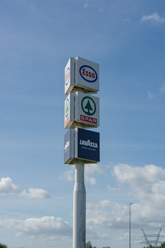 September 24, 2026, Amsterdam, Netherlands - Signpost displaying Esso, SPAR, and Lavazza logos against a blue sky