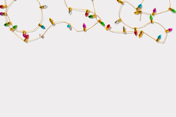 Multicolored bulbs on a golden string on a white background. Christmas holiday greetings with copy space.  © Maja 