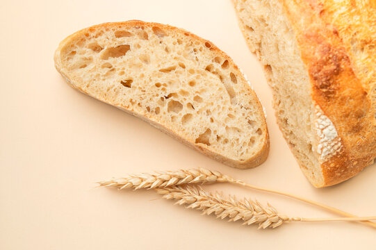 Crusty sourdough bread pieces create food styling on warm beige surface. Bakery advertising can highlight artisan baking, natural ingredients, fresh bread, traditional craft and wholesome eating.