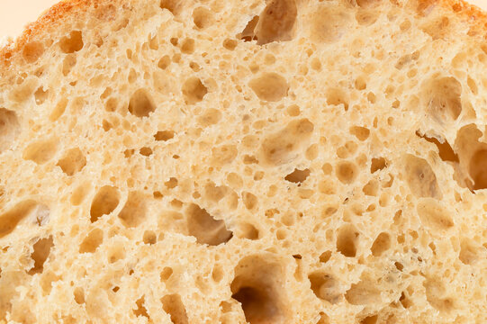 Porous bread crumb fills frame in close-up, showing airy structure and warm wheat color. Baking content can highlight sourdough texture, freshness, fermentation, artisan quality and food detail.
