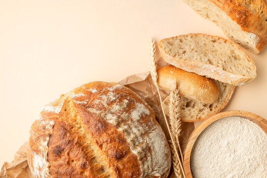Sliced sourdough bread displays golden crust and porous crumb on beige background. Food promotion can present artisan quality, bakery products, fresh baking, rustic texture for menus and campaigns