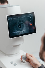 Ophthalmologist hand on joystick of dry eye analyzer, patient eye close-up on screen during tear meniscus height test. Eye examination in ophthalmology clinic, eye care concept © Valeriia Stoganenko