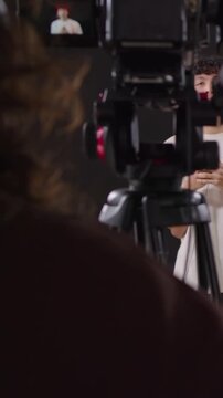 Vertical video: Rolling cam cueing host entering right frame, with mic speaking for cam, copy space