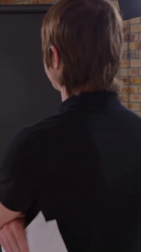 Vertical video: Cam opening cueing man black polo handing script to woman sweater in studio
