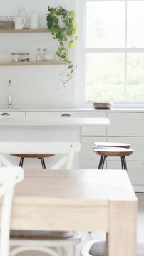 Vertical video: Panning camera revealing wood table, chairs and blue oven in kitchen to show layout
