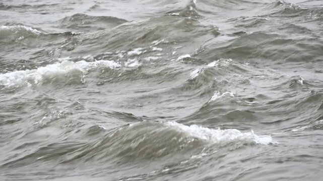 Muddy river water rolling in small whitecaps on an overcast day