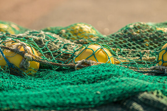 Yellow fishing floats tangled among green commercial fishing nets.