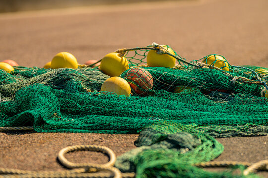Green fishing nets and yellow floats resting on harbor quay.