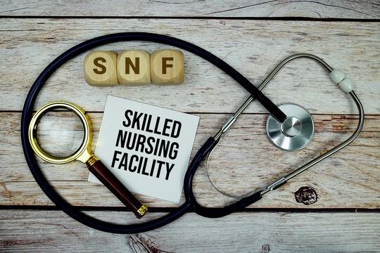 Skilled Nursing Facility (SNF) text with stethoscope and magnifying glass on wooden background