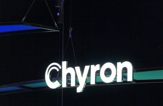 Amsterdam, Netherlands - September 11, 2026: Chyron illuminated logo suspended above colorful geometric display structures at IBC media and technology exhibition