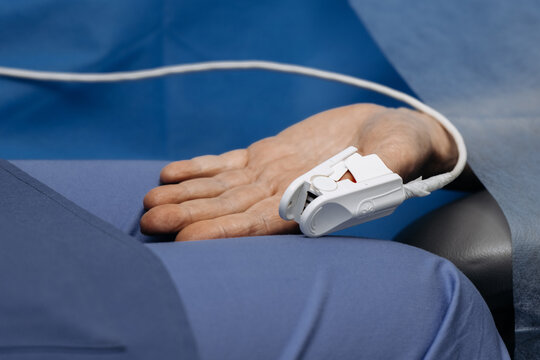 White pulse oximeter sensor attached to a patient's finger. Medical device for monitoring blood oxygen saturation and pulse rate.