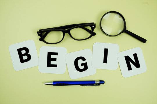 BEGIN alphabet letters with magnifying glass, eye glasses and pen on yellow background