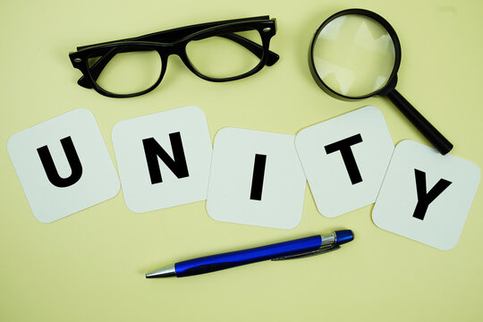 UNITY alphabet letters with magnifying glass, eye glasses and pen on yellow background