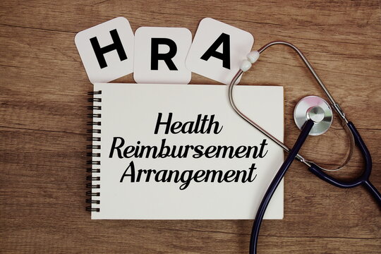 HRA Health Reimbursement Arrangement text written on notepad with stethoscope on wooden background