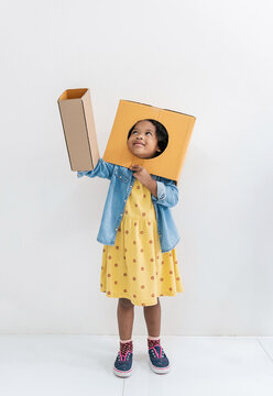Black girl Student in primary school, children creatively playing with cardboard box, pretending, building, and interacting together indoor play space class room. Home school for toddler day care.