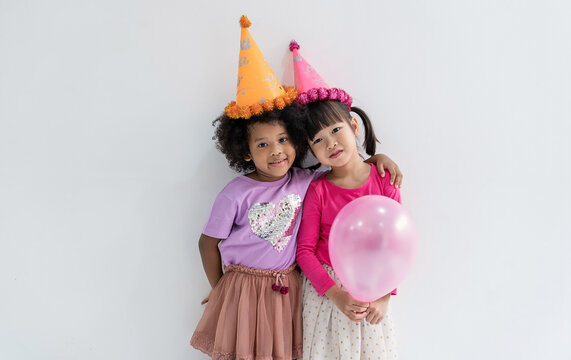Portrait of happy young diverse group children wearing colorful birthday hats  festive outfits, standing together and celebrating a joyful childhood party. Cheerful birthday halloween day celebration.