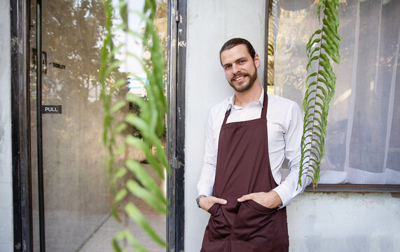 Startup successful sme small business local owner caucasian man barista wear apron stand at the modern coffee shop, welcome customers hospitality, and customer service.
