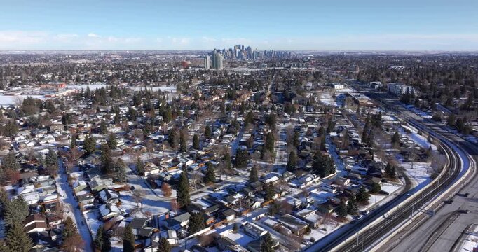 Aerial flyover of a snow-covered residential neighborhood with downtown Calgary in the distance, Alberta, Canada.