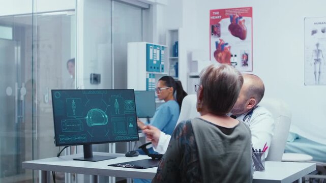 Senior doctor discusses a digital brain scan with an older female patient in a modern medical clinic, using diagnostic imaging to explain examination results and support patient education.
