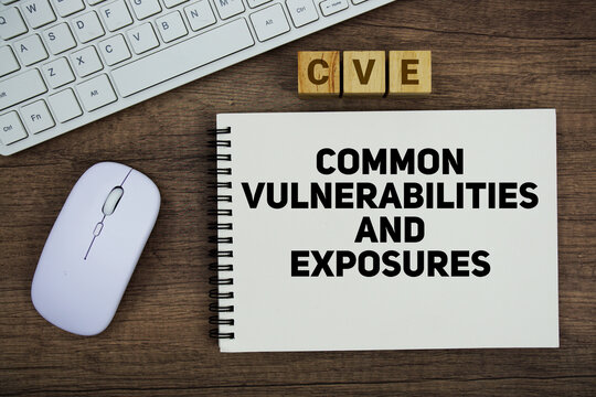 CVE Common Vulnerabilities and Exposures message with keyboard and optical mouse on wooden background