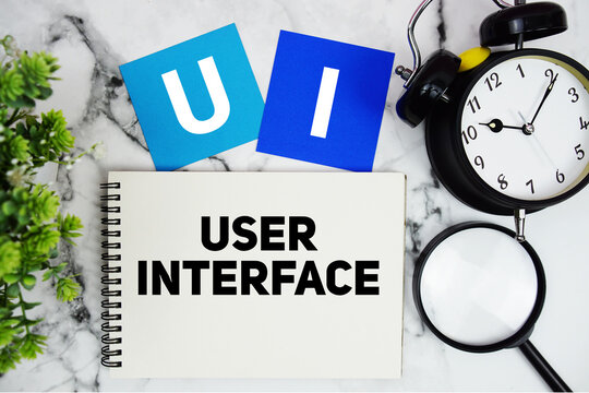 UI User Interface text written on notepad with alarm clock and magnifying glass on marble background