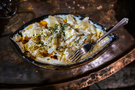 Traditional Bosnian Klepe dumplings with garlic cream sauce, melted butter and paprika in a hot skillet. Sarajevan cuisine.